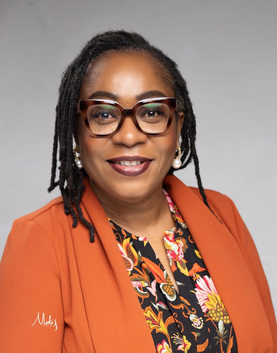 Nneka Otogbolu smiling, wearing an orange blazer
